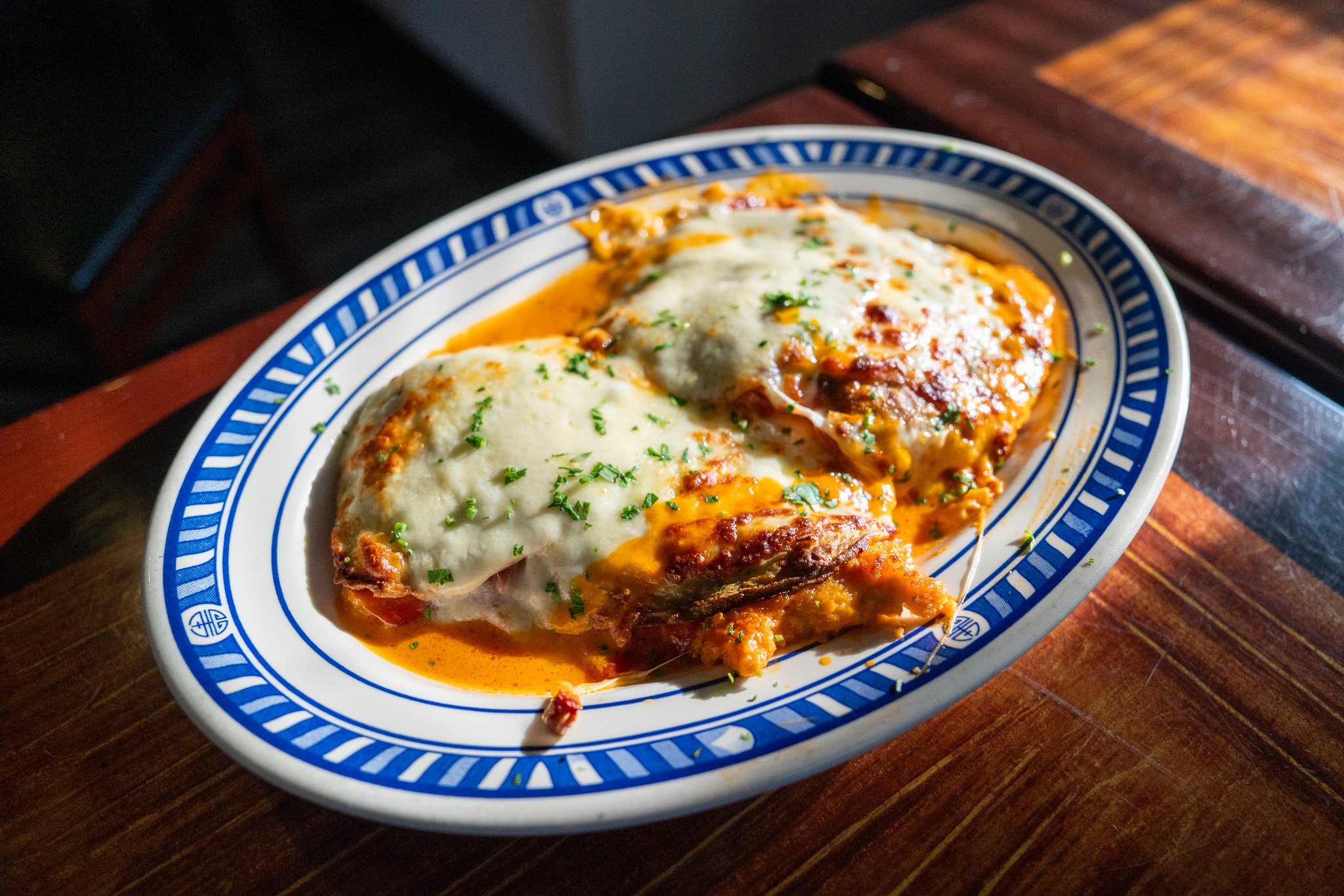 A parmigiana-style dish with melted mozzarella and herbs on a blue-rim plate.