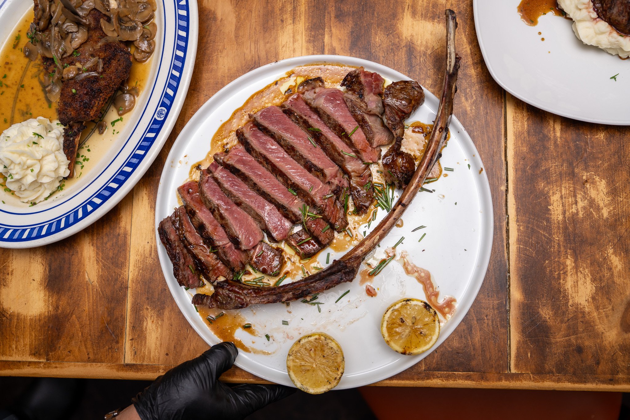 Sliced medium-rare steak with lemon slices on a white plate.